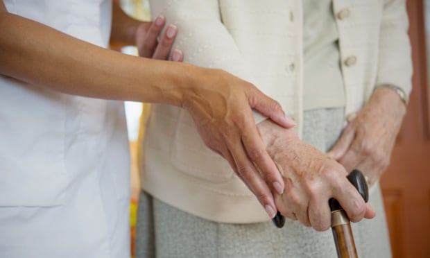 A care worker helping an elderly woman walk