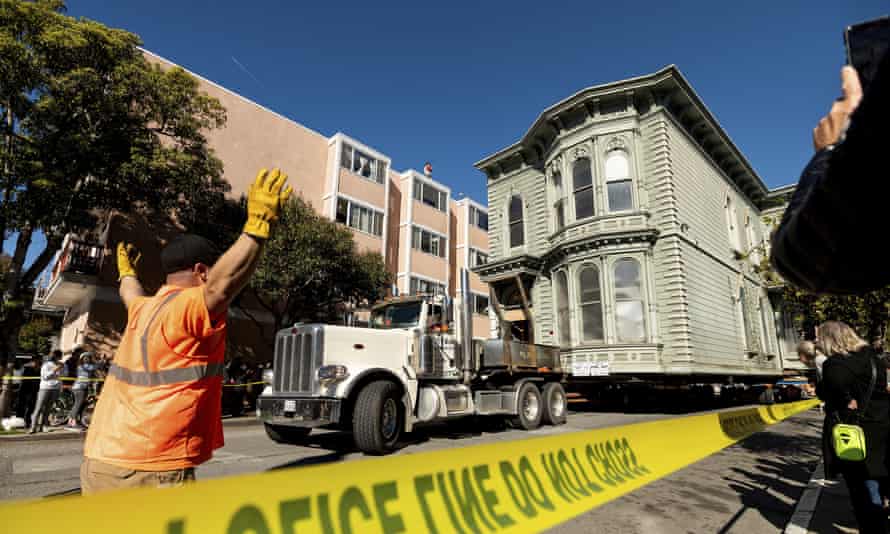 Workers signal a truck driver pulling a Victorian home through San Francisco on Sunday.