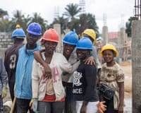 A group of mainly female construction workers pose for the camera in hard hats on a building site