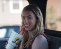 a woman smiling and biting the straw of a drink