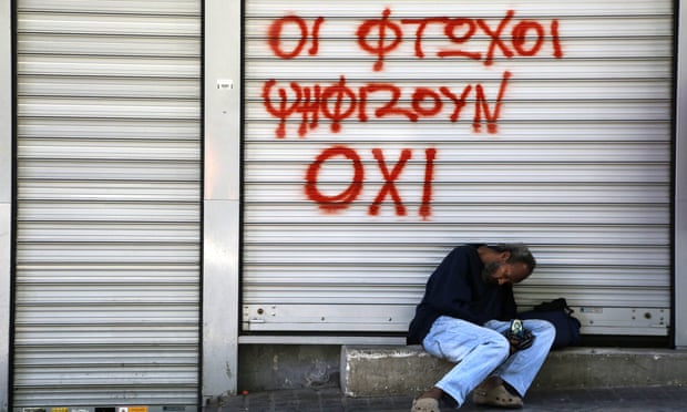 A man sleeps outside a closed shop with graffiti reading ‘Poor vote NO’ in central Athens on Saturday.