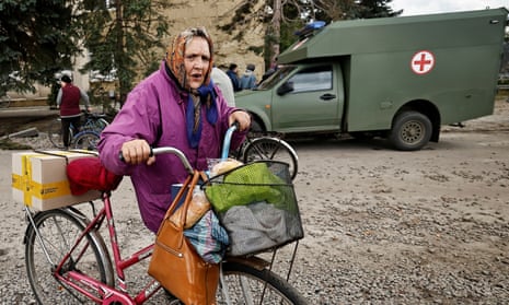 A local resident wheels her bicycle after receiving humanitarian aid in the recently liberated town of Lyman, Donetsk region, Ukraine.