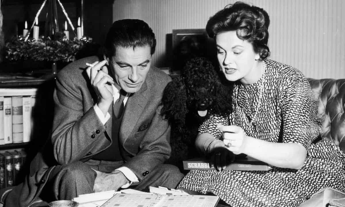 Two people playing Scrabble with their dog