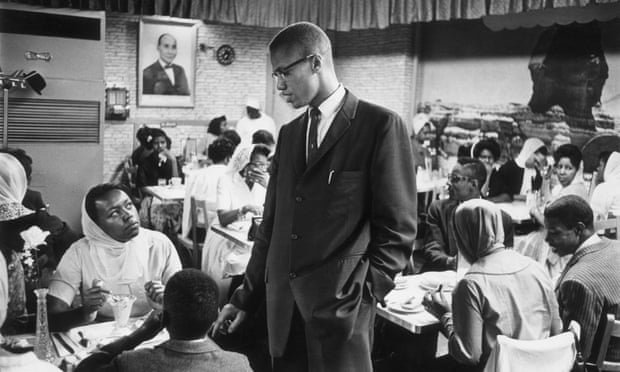 Malcolm X talking to women inside a restaurant in Harlem, New York.