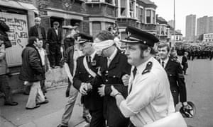 An injured police officer is helped by ambulance staff