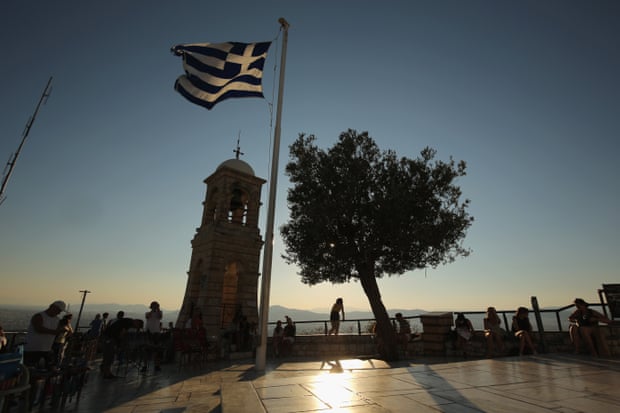 Tourists take in the view over the city of Athens from Lycabettus Hill.
