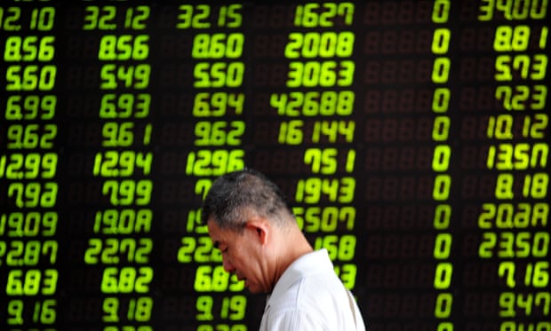 An investor walks past a stock screen in Shenyang, capital of northeast China’s Liaoning Province, July 30, 2015.