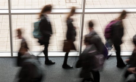 Secondary school pupils moving by a window in a school