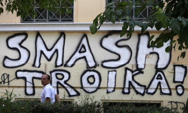 A pedestrian passes graffiti referring to the officials from the European Union, European Central Bank and International Monetary Fund, together known as the troika, in Athens.