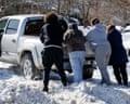 people push a truck out of a snow pile