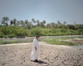 A farmer walks on the cracked, dried earth beside the Diyala river. In recent years the water by his home has become stagnant, poisoned, and is no longer even able to be used for his animals.
