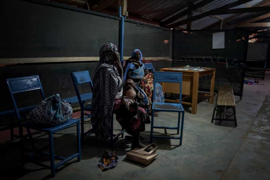 ‘We just pray for rain’: Niger is in the eye of the climate crisis – and children are starving 2 Two mothers sit with their small children on their laps in a dimly lit shed