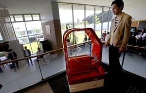 A porter robot, left, escorts a hotel employee while carrying his suitcase.