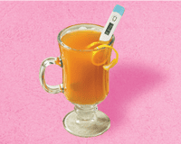 a cup of an orange fluid with a thermometer in it
