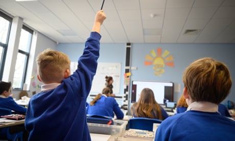 A pupil raises his hand in a classroom