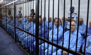 Muammar Gaddafi-era officials wait for their trial in a prison cage in Tripoli.