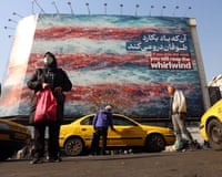 Iranians walk near a huge anti-US billboard hanging at the Enqelab square in Tehran, 27 January 2026.