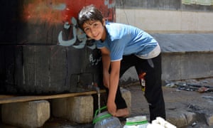 A child fills a container with water in Yarmouk last month. 