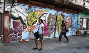 Puerto Ricans walk past a shuttered business in San Juan.