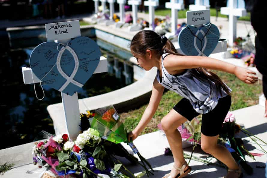 A girl leaves a flower at a monument in Town Square of Yuvarde.