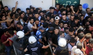 Migrants and refugees are pushed as riot police try to maintain an orderly line during a registration procedure at the national stadium.