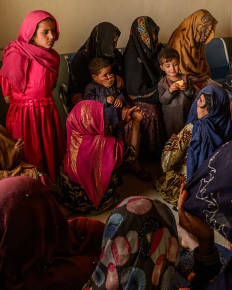 A crowded room of Afghan women, some with children, with all covering their faces