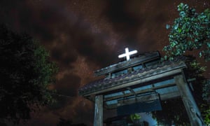 Cross reflects moonlight atop Christian church in Thailand.