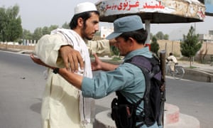 Afghan official frisks a man by the roadside in Kandahar
