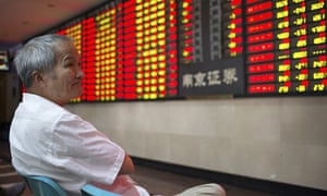 An investor looks at an electronic board showing stock information at a brokerage house in Nanjing