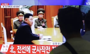 South Koreans watch a television news programme showing footage of Kim Jong-un. The caption reads: 'North Korea orders military to have full combat readiness.'