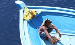 A boy, part of group of 300 sub-Saharan African migrants, sits in a boat during an Italian rescue operation.