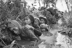 Women and children crouch in a muddy canal as they take cover from intense Viet Cong fire, January 1, 1966