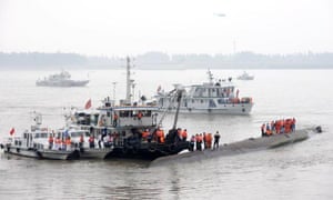 Chinese rescuers stand on the upturned bottom of the capsized cruise ship in the Yangtze River in Jianli county, 