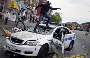 A demonstrators jumps on a damaged Baltimore police department vehicle during clashes in Baltimore.