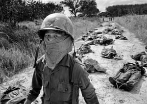 A South Vietnamese stretcher-bearer wears a face mask to protect himself from the smell as he passes the bodies of U.S. and South Vietnamese soldiers killed fighting the Viet Cong in the Michelin rubber plantation, November 27, 1965. More than one hundred bodies were recovered after the Viet Cong overran South Vietnam’s 7th Regiment, 5th Division, killing most of the regiment and several U.S. advisers. The plantation, situated midway between Saigon and the Cambodian border, was the scene of frequent fighting throughout the war