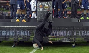 Lowy tumbles from the stage with Melbourne Victory players awaiting the presentation of the trophy at AAMI Park.