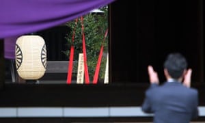 A sacred branch with red ribbons, offered by Shinzo Abe, is seen in the main hall of the Yasukuni war shrine in Tokyo on Tuesday as a man claps hand to offer prayers for people who died during the second world war.