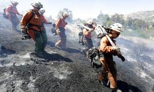 Fire crews walk down a hillside to work on a battle a wildfire near Granada Hills in Los Angeles on Monday.