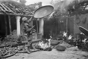 A 1st Cavalry Division soldier throws a rice basket onto the flames as his unit sweeps through a village near Tam Ky, 350 miles northeast of Saigon, October 27, 1967