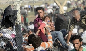 A man carries a girl as Syrians fleeing the war pass through broken down border fences to enter Turkish territory illegally