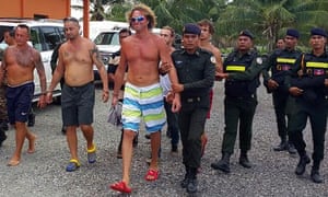 Sergei Polonsky, wearing sunglasses, is escorted away by Cambodian military police.