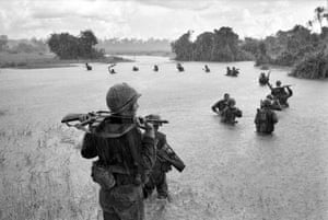 US paratroopers of the 2nd Battalion, 173rd Airborne Brigade, hold their automatic weapons above water as they cross a river in the rain during a search for Viet Cong positions in the jungle area of Ben Cat, September 25, 1965