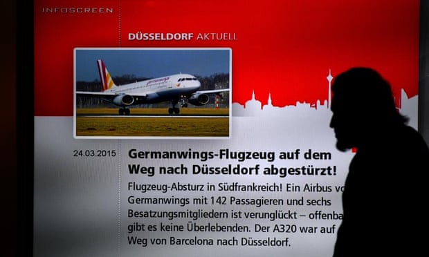 A man walks past a screen displaying news of the crash at the airport in Düsseldorf, where the Germanwings plane was due to land.