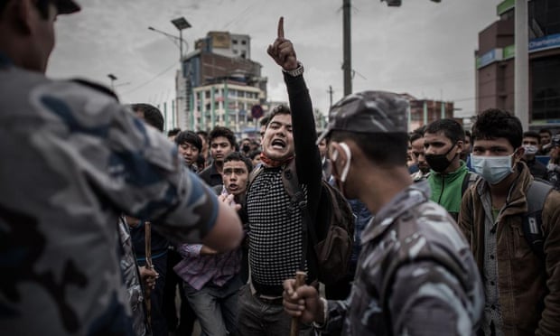 Nepalese riot police officials stand alert on a street in Kathmandu as earthquake survivors desperate to leave the Nepalese capital show their anger after promised special bus services failed to materialise.