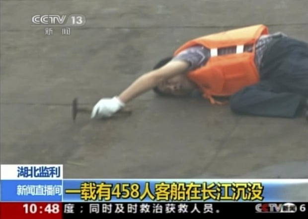 In this image taken from video released by China’s CCTV, a rescue worker listens for a response as he taps on the hull of the capsized ship.