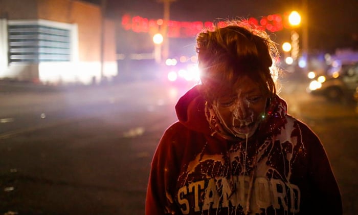 A protester stands in the street after being treated for tear gas exposure in Ferguson