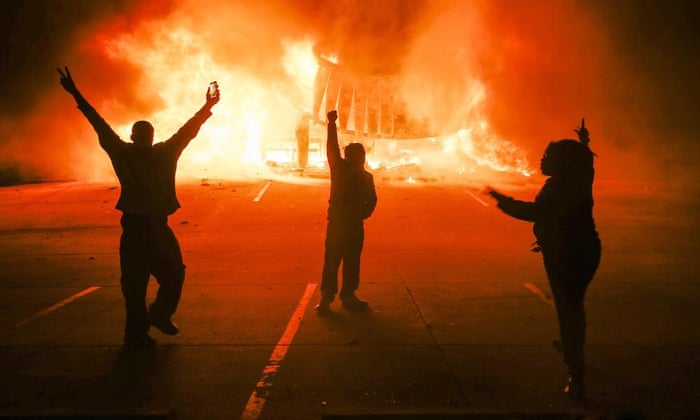 Protestors parade in the parking lot of a burning auto parts store in Ferguson