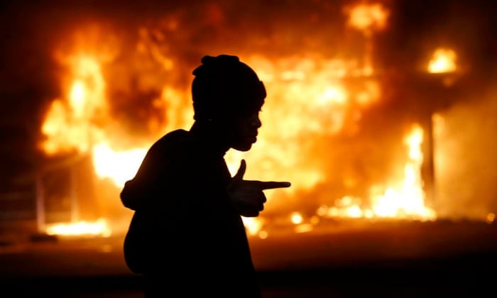 A man walks past a burning building during protests in Ferguson