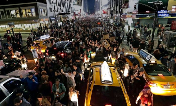 Thousands of protesters march up Seventh Avenue through oncoming traffic to Times Square