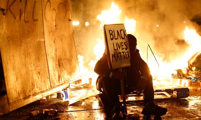 A demonstrator sits in front of a street fire in Ferguson